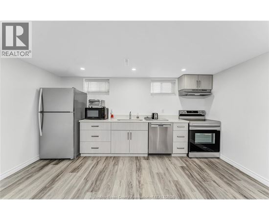 A kitchen with a refrigerator, microwave, oven, and sink.