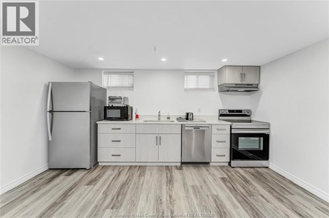 A kitchen with a refrigerator, microwave, oven, and sink.