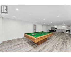A pool table in a room with wooden flooring and a white wall.
