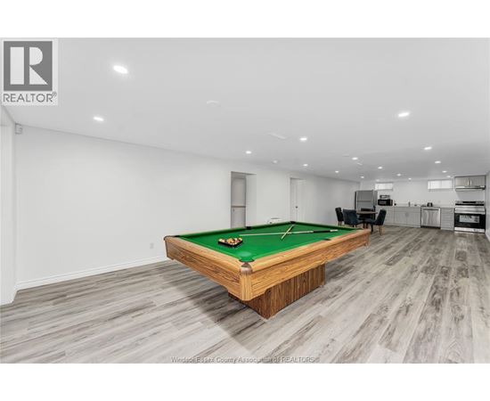 A pool table in a room with wooden flooring and a white wall.