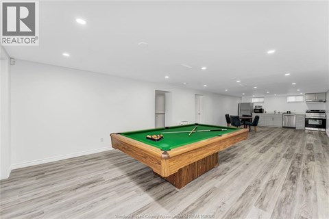 A pool table in a room with wooden flooring and a white wall.