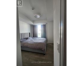 A bedroom with a bed, a window with curtains, and a ceiling light.