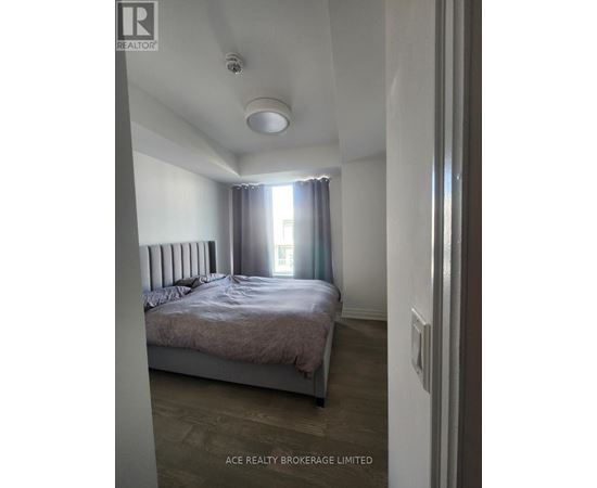 A bedroom with a bed, a window with curtains, and a ceiling light.