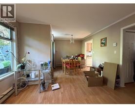 A room with a dining table and chairs in the middle of the room with boxes on the floor.