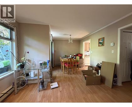 A room with a dining table and chairs in the middle of the room with boxes on the floor.