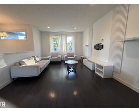 A living room with a white couch, a coffee table, and a television.
