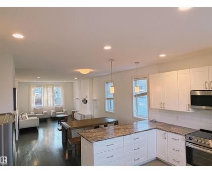 A modern kitchen with white cabinets and a granite countertop.