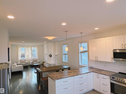 A modern kitchen with white cabinets and a granite countertop.