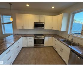 A kitchen with white cabinets and a granite countertop.