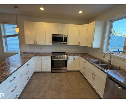 A kitchen with white cabinets and a granite countertop.