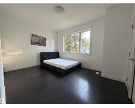 A bedroom with a bed, a window, and a picture on the wall.