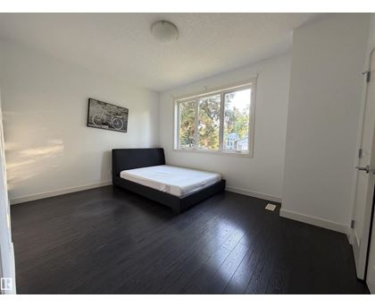 A bedroom with a bed, a window, and a picture on the wall.