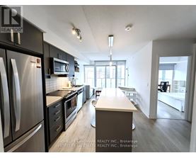 A kitchen with a refrigerator, microwave, and oven.