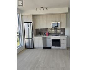 A kitchen with a refrigerator, oven, and sink.