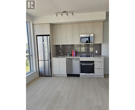 A kitchen with a refrigerator, oven, and sink.