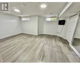 A spacious room with wooden flooring and white walls.