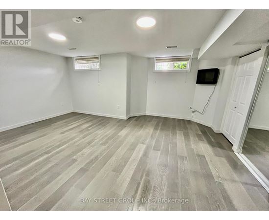 A spacious room with wooden flooring and white walls.