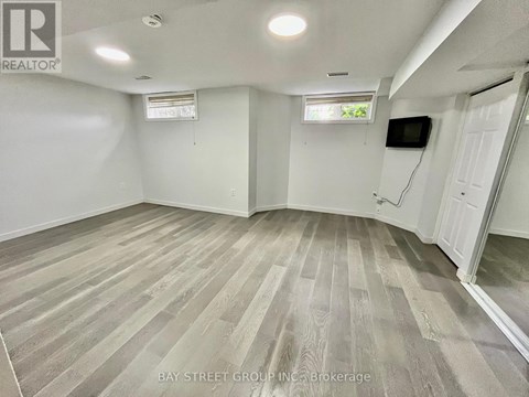 A spacious room with wooden flooring and white walls.