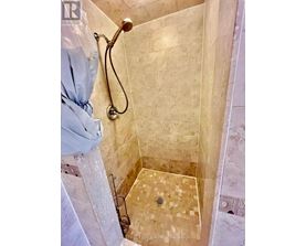 A shower with a tiled floor and walls.