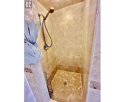 A shower with a tiled floor and walls.