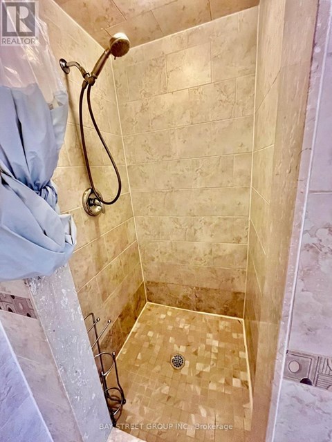 A shower with a tiled floor and walls.