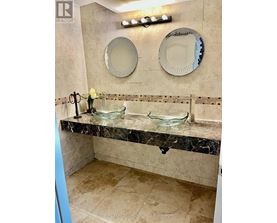 A bathroom with a marble counter top and two mirrors.