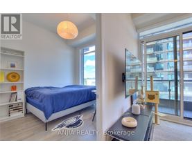 A bedroom with a blue bedspread and a balcony with a glass door.
