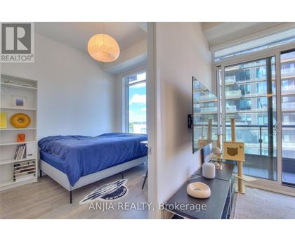 A bedroom with a blue bedspread and a balcony with a glass door.