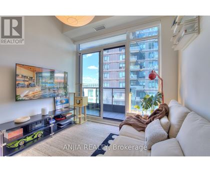 A living room with a white couch and a large window with a view of a building.