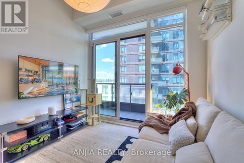 A living room with a white couch and a large window with a view of a building.