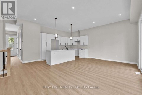 A spacious, empty room with wooden floors and white walls.
