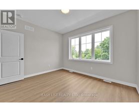 A room with a white door and a window with a view of trees outside.