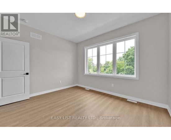 A room with a white door and a window with a view of trees outside.