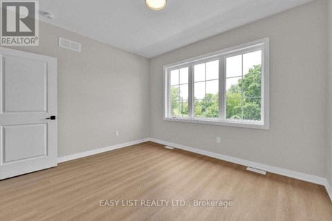 A room with a white door and a window with a view of trees outside.