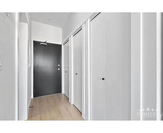 A hallway with white walls and a black door.