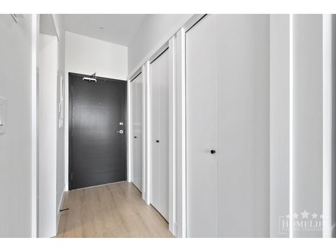 A hallway with white walls and a black door.