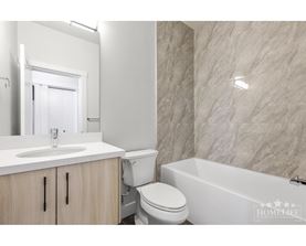 A white bathroom with a marble wall and a white bathtub.