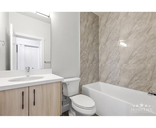 A white bathroom with a marble wall and a white bathtub.