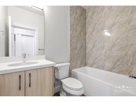 A white bathroom with a marble wall and a white bathtub.