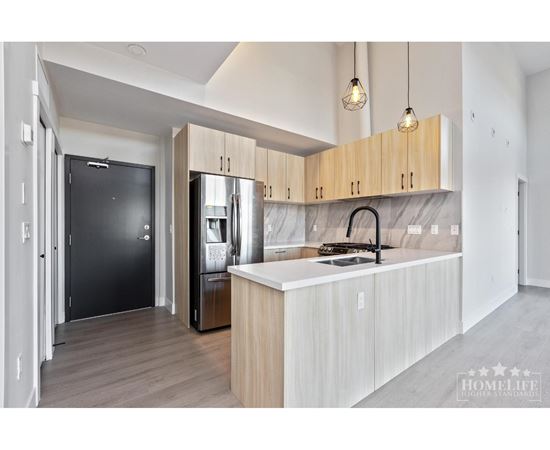 A modern kitchen with a black fridge and wooden cabinets.