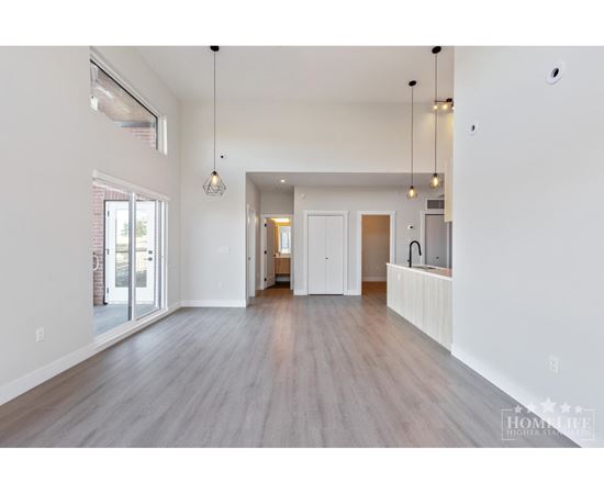 A spacious living room with wood flooring and white walls.