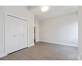 A room with a white wall and a white closet with two doors.