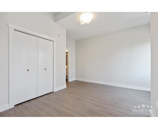 A room with a white wall and a white closet with two doors.