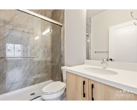 A modern bathroom with a marble shower and a white toilet.