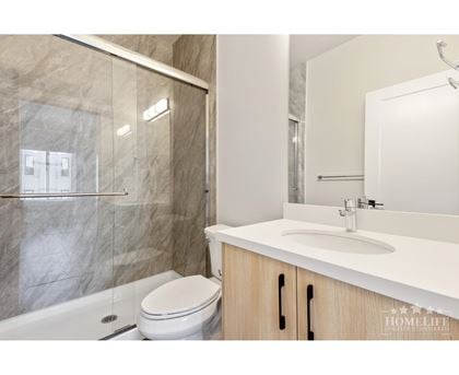 A modern bathroom with a marble shower and a white toilet.