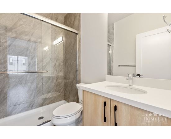 A modern bathroom with a marble shower and a white toilet.