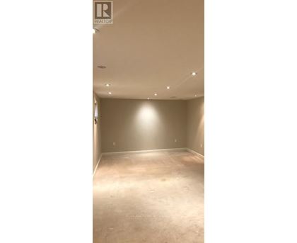 A spacious room with a light brown carpet and beige walls.