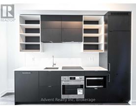 A modern kitchen with a black refrigerator and stove top oven.