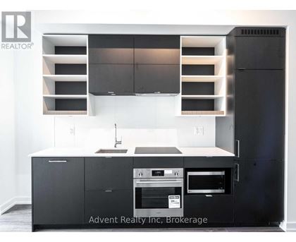 A modern kitchen with a black refrigerator and stove top oven.