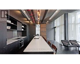 A modern kitchen with a long white table and chairs.